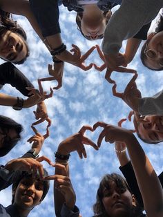 a group of people standing in a circle holding their hands up to form the shape of a heart