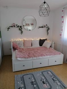 a white bed with pink blankets and pillows