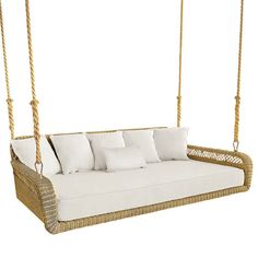 a wicker swing bed with white pillows on the front and back cushions, hanging from a rope