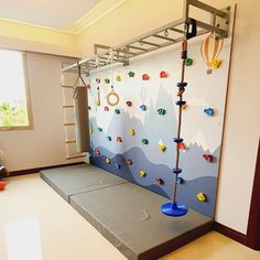 a child's play area with climbing ropes and toys on the wall, in front of a window