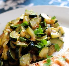 grilled chicken with zucchini, squash and parsley on a white plate