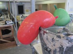 two large red and green peppers sitting on top of a metal bucket in a factory