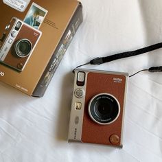 an old camera sitting on top of a bed next to a box