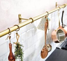 pots and pans are hanging on the wall in this kitchen with brass handles,