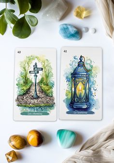 two tarot cards sitting on top of a table next to stones