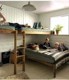 three children laying on bunk beds in a room with two adults and one child reading