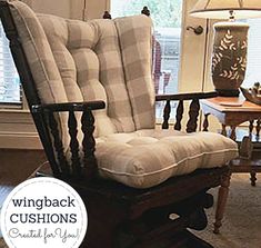 a rocking chair in front of a window with a lamp on the table next to it