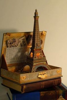 an open book with the eiffel tower in it sitting on top of some books