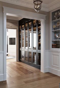 an empty room with wooden floors and glass doors on the front door is lit by a chandelier