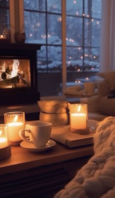 candles are lit on a coffee table in front of a fireplace