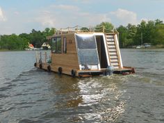 a houseboat floating on top of a body of water with stairs leading up to the roof