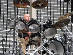 a man is playing drums on stage in front of a wall with metal bars behind him