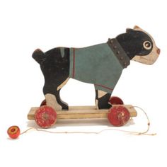 a wooden toy dog riding on a skateboard