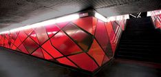 an escalator with red and black tiles on the wall next to some stairs