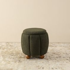 a small green stool sitting on top of a marble floor next to a white wall