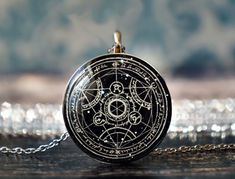 a black and white photo of a pentagramil pendant on a chain with some silver beads in the background