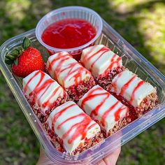 a person holding up a plastic container filled with desserts and strawberries next to ketchup