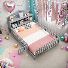 a child's bed with pink and white sheets in a room filled with balloons