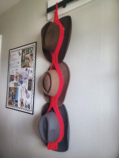 three hats are hanging on the wall next to a hat rack with two hats in it