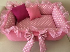 pink and white polka dot dog bed with bows on the bottom, two pillows in front