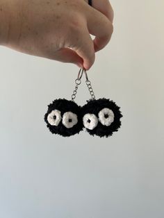 a hand holding two black and white eyes on a keychain that is hanging from a chain