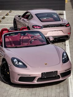 two pink sports cars parked next to each other