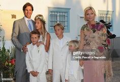 a family posing for a photo in front of a building with flowers and greenery