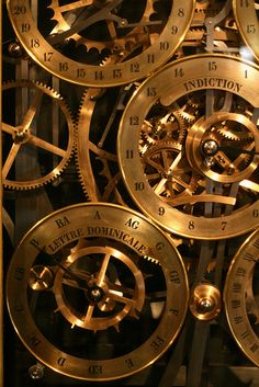 several gold clocks with roman numerals and numbers on the sides, all connected together