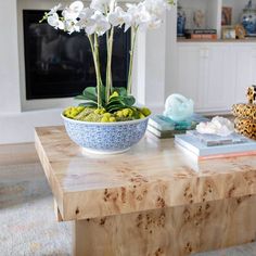 white flowers in a blue and white bowl on a coffee table with other decor items