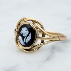 Dieser frühe viktorianische Trauerring aus 14 Karat Gold zeigt einen einfachen schwarz-weißen Achat mit einer handgeschnitzten Vergissmeinnicht-Blumenkamee; Der Ringkopf besteht aus einem Golddraht, der sich wie ein Knoten um die Kamee windet, das Band besteht aus drei zusammengelöteten Abschnitten aus Golddraht.  Dieses Stück wurde in Erinnerung an einen geliebten Menschen getragen und trägt eine handgravierte Inschrift auf der Innenseite der Banderole.  Der Name ist nicht ganz klar, aber die g Rings Statement, Statement Rings, Jewelry Rings, Gold