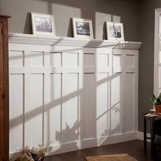 a living room filled with furniture and pictures hanging on the wall above it's windows