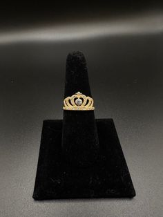 a gold ring with a diamond on it sitting on top of a black velvet stand