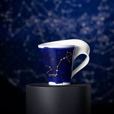 a coffee cup sitting on top of a black stand next to a blue background with stars