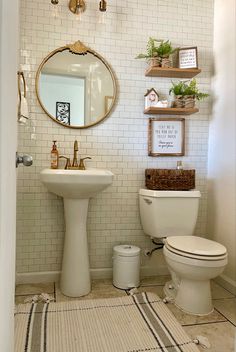 a white toilet sitting next to a sink in a bathroom under a mirror and shelves