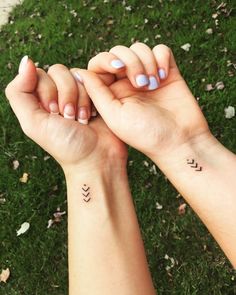 two hands holding each other with small tattoos on their wrist and the words love are written in cursive letters