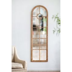 an arched window is hung on the wall next to a chair and potted plant