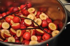 red berries and bananas are being cooked in a pot on the stove top, with sticks sticking out of them