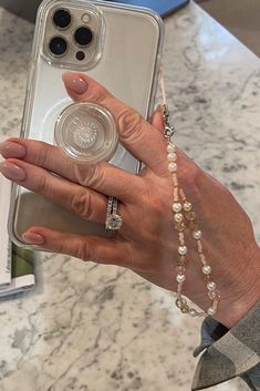 a woman is holding up her phone case with pearls on the bottom and one hand