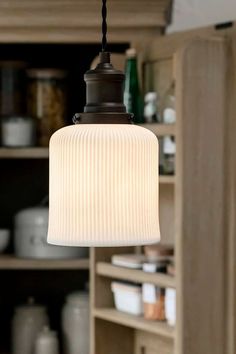 a light that is hanging from a ceiling in a room with shelves and cupboards