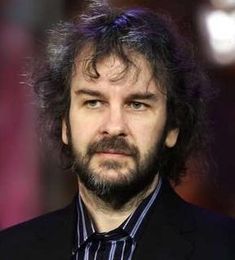 a man with long hair and beard wearing a black suit, striped shirt and tie