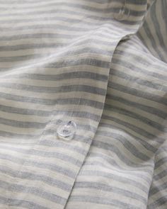 close up view of the collar and sleeves of a striped shirt with buttons on it