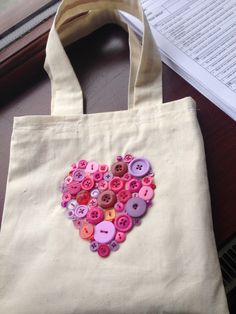 a tote bag with buttons in the shape of a heart sitting on a table