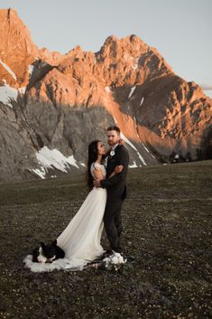 a bride and groom standing in front of mountains