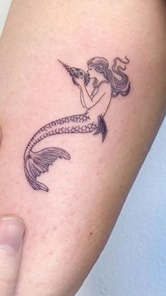 a woman with a mermaid tattoo on her arm