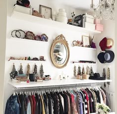 a closet with lots of clothes hanging on the wall and a large mirror above it