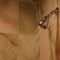 a shower head with water coming out of it's spout in a tiled bathroom