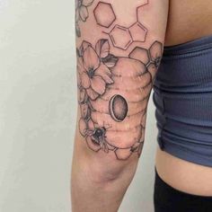 a woman's arm with flowers and honeycombs on the left side of her body