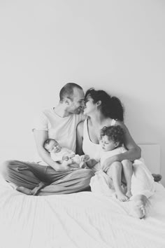 a man, woman and child are sitting on a bed with their heads close to each other