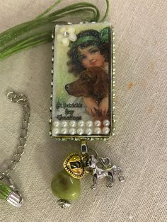 a necklace with an image of a woman and a dog on it next to a beaded bracelet