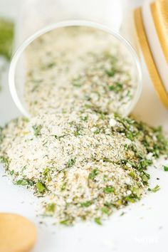 a bowl filled with chopped herbs next to a wooden spoon on top of a table